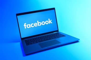 Prague, Czechia - 08 12 2025: A dynamic view of a laptop on a uniform background displaying the Facebook logo. Facebook is a social media platform for connecting and sharing content.