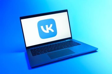 Prague, Czechia - 08 12 2025: A dynamic view of a laptop on a uniform background displaying the VK logo. VK is a social media platform for connecting and sharing content.