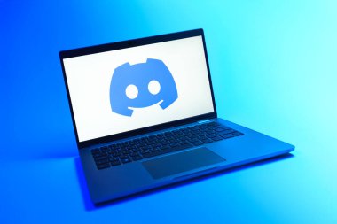 Prague, Czechia - 08 12 2025: A dynamic view of a laptop on a uniform background displaying the Discord logo. Discord is a platform for voice, video, and text communication.