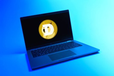 Prague, Czechia - 08 12 2025: A dynamic view of a laptop on a uniform background displaying the Dogecoin logo. Dogecoin is a cryptocurrency used for peer-to-peer transactions.