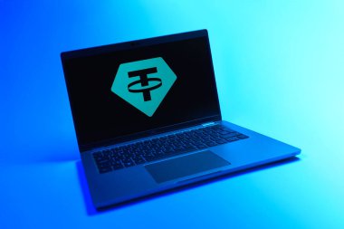 Prague, Czechia - 08 12 2025: A dynamic view of a laptop on a uniform background displaying the Tether logo. Tether is a digital cryptocurrency pegged to the US dollar.