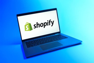 Prague, Czechia - 08 12 2025: A dynamic view of a laptop on a uniform background displaying the Shopify logo. Shopify is a platform for creating and managing online stores.