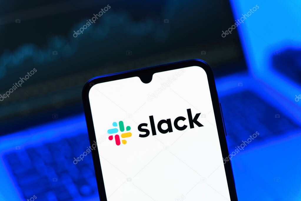 Prague, Czechia - 08 12 2025: A mobile phone standing in front of a laptop displays the Slack logo. Slack is a platform for team messaging and workplace communication.