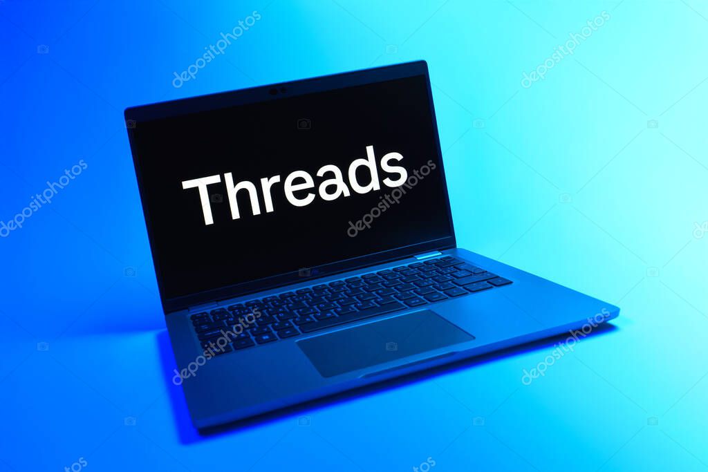 Prague, Czechia - 08 12 2025: A dynamic view of a laptop on a uniform background displaying the Threads logo. Threads is a social media platform for sharing short posts and updates.