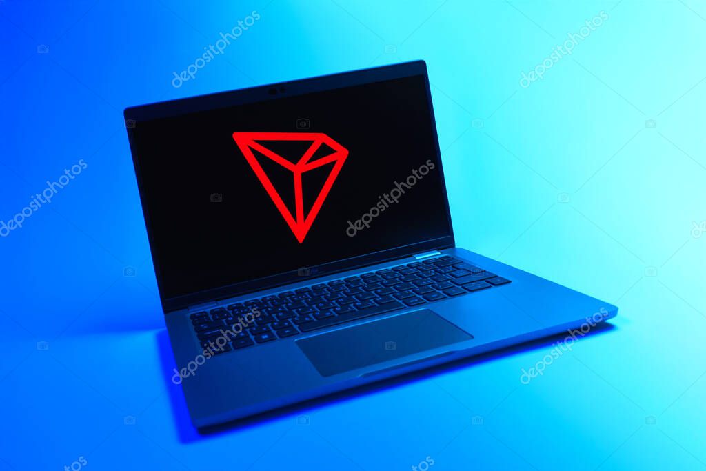 Prague, Czechia - 08 12 2025: A dynamic view of a laptop on a uniform background displaying the Tron logo. Tron is a blockchain platform for decentralized applications.