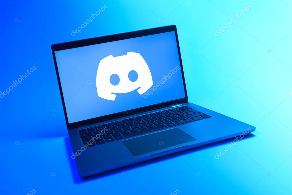 Prague, Czechia - 08 12 2025: A dynamic view of a laptop on a uniform background displaying the Discord logo. Discord is a platform for voice, video, and text communication.