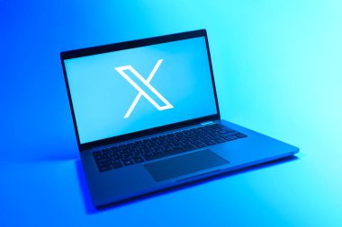 Prague, Czechia - 08 12 2025: A dynamic view of a laptop on a uniform background displaying the X logo. X is a platform for sharing short posts and updates.