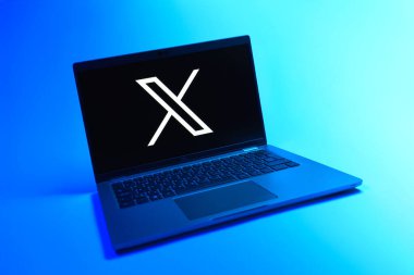 Prague, Czechia - 08 12 2025: A dynamic view of a laptop on a uniform background displaying the X logo. X is a platform for sharing short posts and updates.