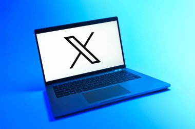 Prague, Czechia - 08 12 2025: A dynamic view of a laptop on a uniform background displaying the X logo. X is a platform for sharing short posts and updates.