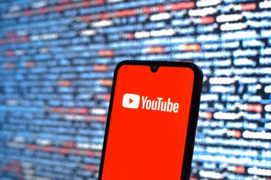 Prague, Czechia - 08 12 2025: Phone in front of a screen showing the Youtube logo. Youtube is a platform to watch and share videos worldwide.