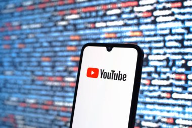 Prague, Czechia - 08 12 2025: Phone in front of a screen showing the Youtube logo. Youtube is a platform to watch and share videos worldwide.