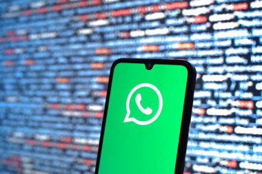 Prague, Czechia - 08 12 2025: Phone in front of a screen showing the WhatsApp logo. WhatsApp is an app for sending texts, calls, and media.