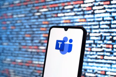 Prague, Czechia - 08 12 2025: Phone in front of a screen showing the Teams logo. Teams is a platform for team collaboration, meetings, and communication.