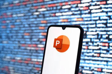 Prague, Czechia - 08 12 2025: Phone in front of a screen showing the Powerpoint logo. Powerpoint is a software for creating presentations and slideshows.