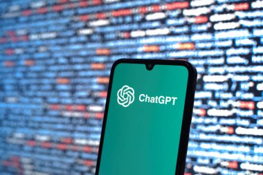 Prague, Czechia - 08 12 2025: Phone in front of a screen showing the ChatGPT logo. ChatGPT is an AI chatbot for generating text and answering questions.