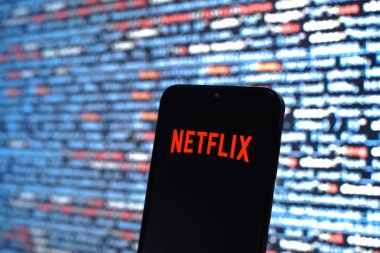 Prague, Czechia - 08 12 2025: Phone in front of a screen showing the Netflix logo. Netflix is a streaming platform for movies and TV shows.