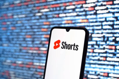 Prague, Czechia - 08 12 2025: Phone in front of a screen showing the Youtube Shorts logo. Youtube Shorts is a platform for short-form video content.