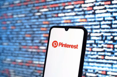 Prague, Czechia - 08 12 2025: Phone in front of a screen showing the Pinterest logo. Pinterest is a platform for discovering and saving ideas visually.
