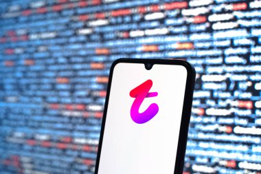 Prague, Czechia - 08 12 2025: Phone in front of a screen showing the Tango logo. Tango is a social app for video calls, messaging, and live streaming.