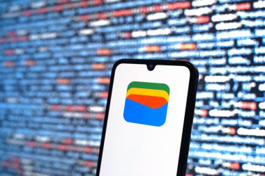 Prague, Czechia - 08 12 2025: Phone in front of a screen showing the Google Wallet logo. Google Wallet is a platform for storing and using digital payment methods.