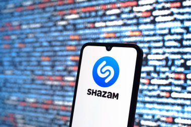 Prague, Czechia - 08 12 2025: Phone in front of a screen showing the Shazam logo. Shazam is an app for identifying songs and music tracks.