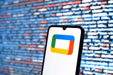 Prague, Czechia - 08 12 2025: Phone in front of a screen showing the Google TV logo. Google TV is a platform for streaming movies, shows, and apps.