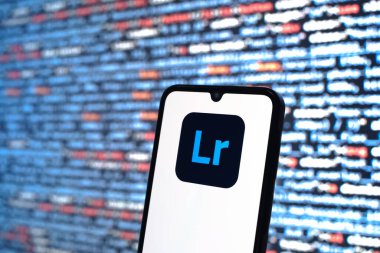Prague, Czechia - 08 12 2025: Phone in front of a screen showing the Lightroom logo. Lightroom is a software for photo editing and management.