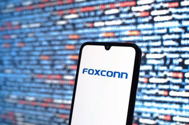 Prague, Czechia - 08 12 2025: Phone in front of a screen showing the Foxconn logo. Foxconn is a company manufacturing electronics and components.