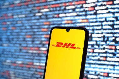 Prague, Czechia - 08 12 2025: Phone in front of a screen showing the DHL logo. DHL is a logistics company offering international shipping services.