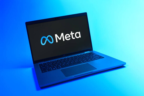 Prague, Czechia - 08 12 2025: A dynamic view of a laptop on a uniform background displaying the Meta logo. Meta is a company offering social platforms like Facebook and Instagram.