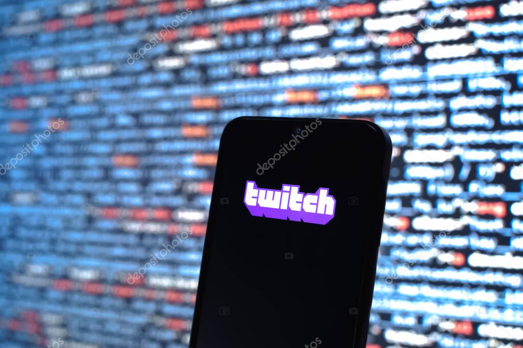 Prague, Czechia - 08 12 2025: Phone in front of a screen showing the Twitch logo. Twitch is a platform for live streaming games and content.