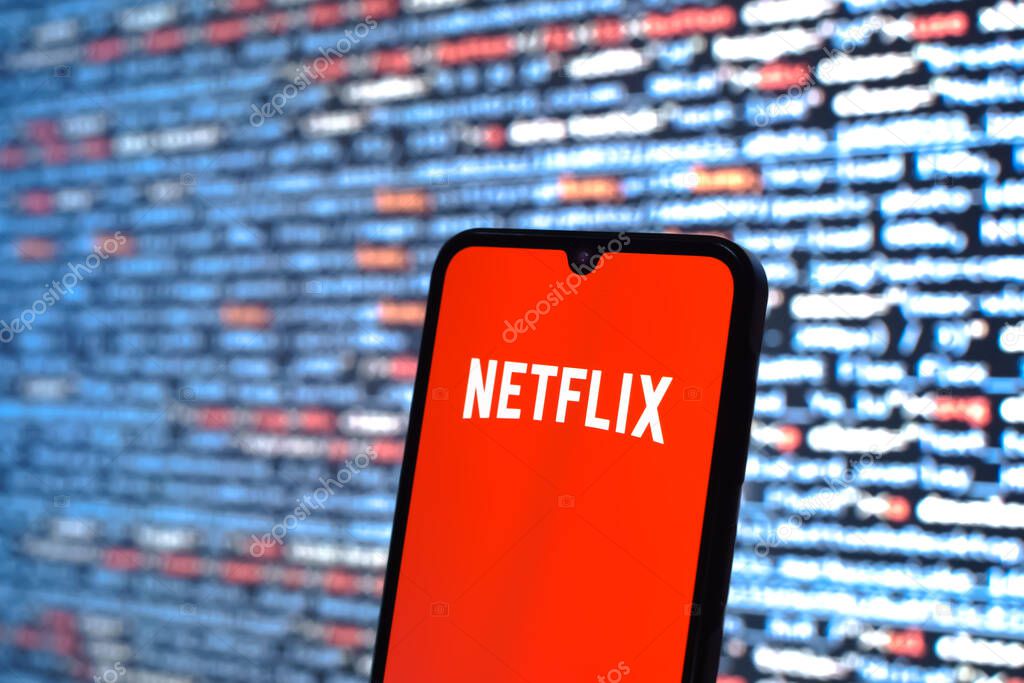 Prague, Czechia - 08 12 2025: Phone in front of a screen showing the Netflix logo. Netflix is a streaming platform for movies and TV shows.