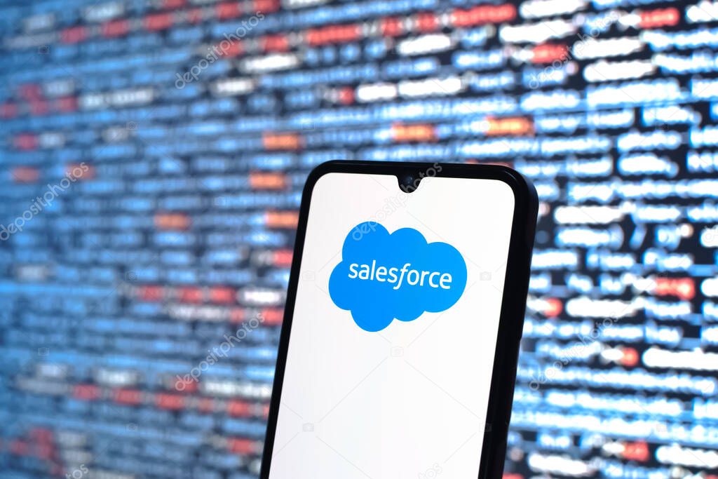 Prague, Czechia - 08 12 2025: Phone in front of a screen showing the Salesforce logo. Salesforce is a platform for customer relationship management and cloud services.