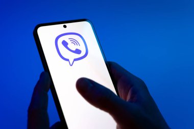 Prag, Çek Cumhuriyeti - 08 12 2025: Mavi arkaplandaki eller Viber logosunu gösteren bir cep telefonu tutuyor. Viber aramalar, mesajlar ve medya paylaşımı için bir mesajlaşma uygulamasıdır.