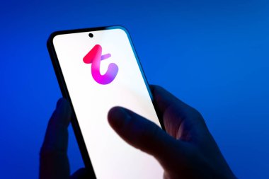 Prag, Çek Cumhuriyeti - 08 12 2025: Mavi arkaplandaki eller Tango logosunu gösteren bir cep telefonu tutuyor. Tango, görüntülü aramalar, mesajlar ve canlı yayınlar için sosyal bir uygulama..