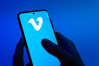 Prag, Çek Cumhuriyeti - 08 12 2025: Mavi arkaplandaki eller Vimeo logosunu gösteren bir cep telefonu tutuyor. Vimeo, yüksek kaliteli video sunucu ve paylaşımı için bir platformdur.