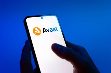 Prag, Çek Cumhuriyeti - 08 12 2025: Mavi arkaplandaki eller Avast logosunu gösteren bir cep telefonu tutuyor. Avast antivirüs ve siber güvenlik için bir platformdur.