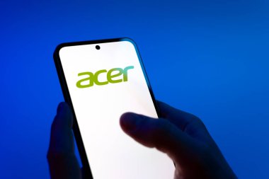 Prag, Çek Cumhuriyeti - 08 12 2025: Mavi arkaplandaki eller Acer logosunu gösteren bir cep telefonu tutuyor. Acer bilgisayar ve elektronik üreten bir teknoloji şirketidir..