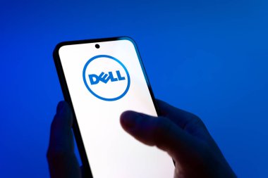 Prag, Çek Cumhuriyeti - 08 12 2025: Mavi arkaplandaki eller Dell logosunu gösteren bir cep telefonu tutuyor. Dell bilgisayar ve bilişim çözümleri üreten bir teknoloji şirketidir..