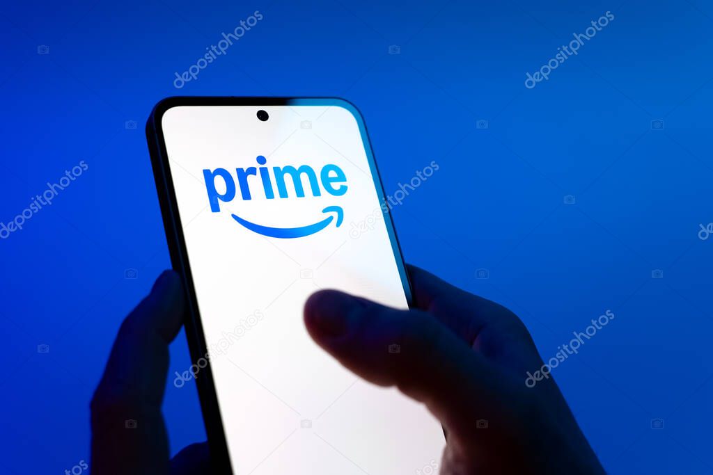 Prague, Czechia - 08 12 2025: Hands on a blue background are holding a mobile phone displaying the Prime logo. Prime is a subscription service for shopping, streaming, and benefits.