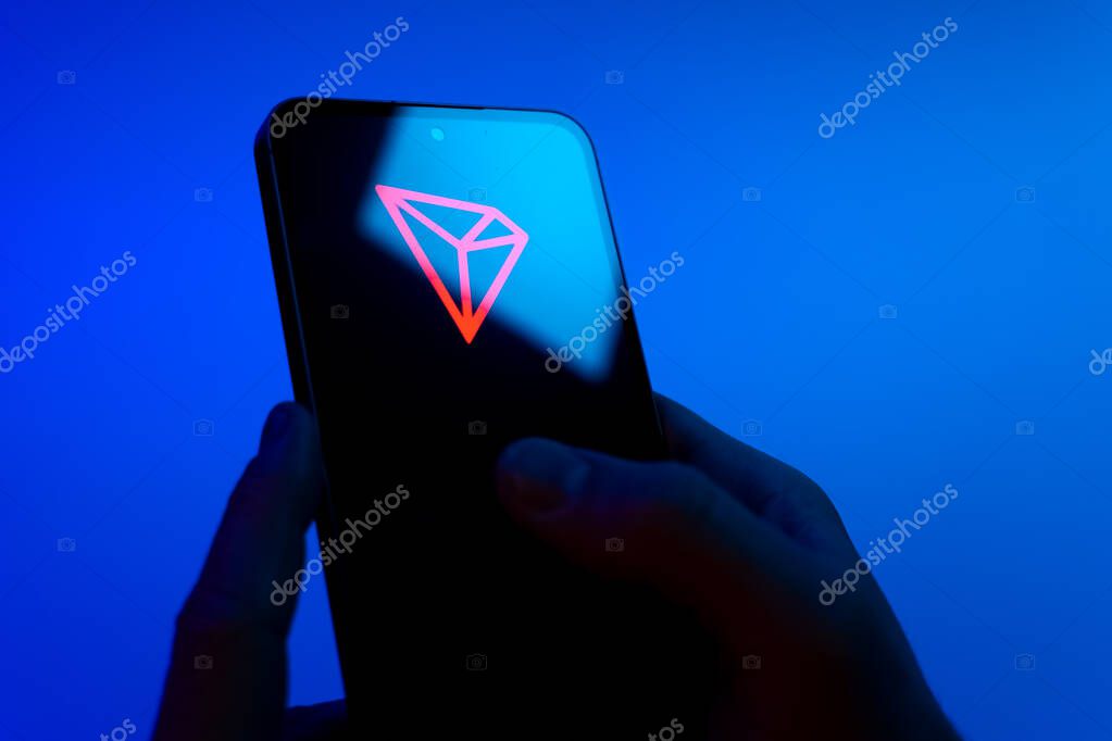 Prague, Czechia - 08 12 2025: Hands on a blue background are holding a mobile phone displaying the Discord logo. Discord is a platform for voice, video, and text communication.