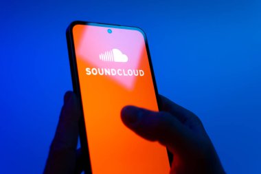 Prag, Çek Cumhuriyeti - 08 12 2025: Eller mavi arkaplanda Discord logosunu gösteren bir cep telefonu tutuyor. Discord ses, video ve metin iletişimi için bir platformdur..