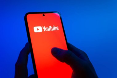 Prag, Çek Cumhuriyeti - 08 12 2025: Eller mavi arkaplanda Discord logosunu gösteren bir cep telefonu tutuyor. Discord ses, video ve metin iletişimi için bir platformdur..