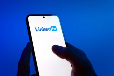 Prag, Çek Cumhuriyeti - 08 12 2025: Eller mavi arkaplanda Discord logosunu gösteren bir cep telefonu tutuyor. Discord ses, video ve metin iletişimi için bir platformdur..