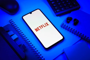 Prag, Çek Cumhuriyeti - 08 18 2025: Merkezde Netflix logosunu gösteren bir cep telefonu ile ofis malzemeleri düzenlemesi. Netflix sinema ve televizyon programları için bir yayın platformudur..