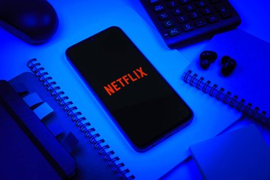 Prag, Çek Cumhuriyeti - 08 18 2025: Merkezde Netflix logosunu gösteren bir cep telefonu ile ofis malzemeleri düzenlemesi. Netflix sinema ve televizyon programları için bir yayın platformudur..