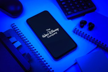 Prag, Çek Cumhuriyeti - 08 18 2025: Merkezde Walt Disney logosunu gösteren bir cep telefonu ile ofis malzemeleri düzenlemesi. Walt Disney film, park ve medya için bir eğlence şirketidir..