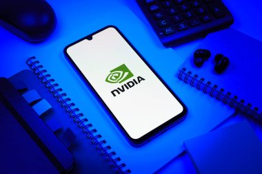 Prag, Çek Cumhuriyeti - 08 18 2025: Merkezinde NVIDIA logosu bulunan bir cep telefonu ile ofis malzemeleri düzenlemesi. NVIDIA, GPU ve yapay zeka donanımı alanında uzmanlaşmış bir teknoloji şirketidir..