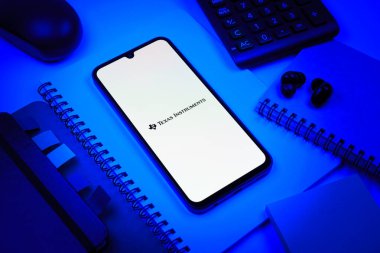 Prag, Çek Cumhuriyeti - 08 18 2025: Merkezinde Texas Instruments logosu bulunan bir cep telefonu ile ofis malzemeleri düzenlemesi. Texas Instruments yarı iletken ve elektronik üreten bir şirket..