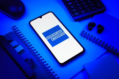 Prag, Çek Cumhuriyeti - 08 18 2025: Merkezde American Express logosunu gösteren bir cep telefonu ile ofis malzemeleri düzenlemesi. American Express kart ve bankacılık sunan bir finans şirketidir..